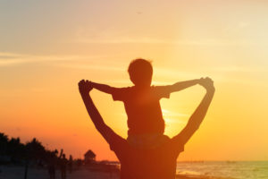 father and son having fun on sunset beach